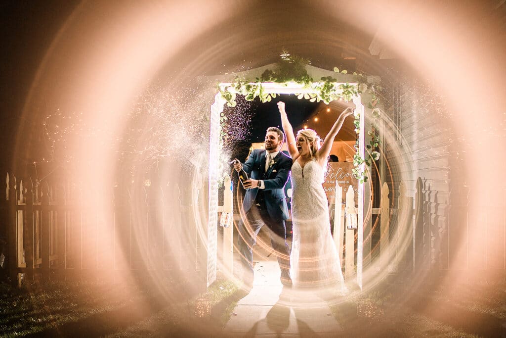 bride throwing her hands up at wedding pergola by Roy Serafin Photo Company