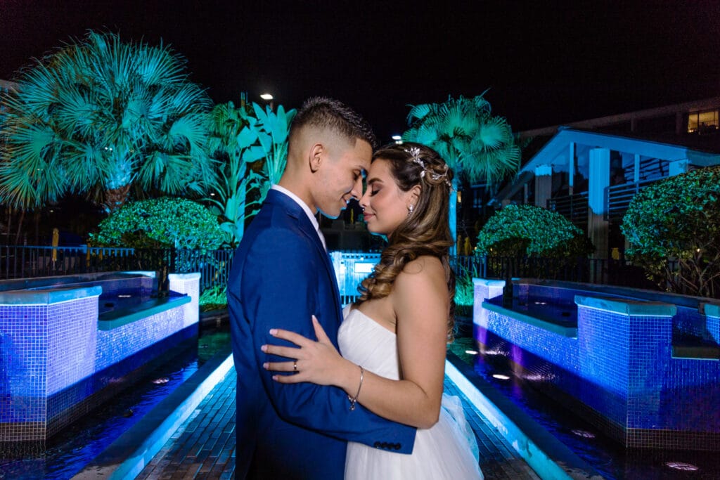 bride and groom embrace at night in a garden with moody blue lights
