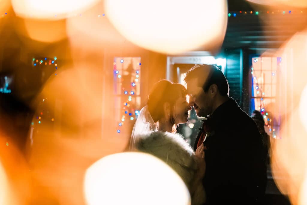 lights reflected as bride and groom kiss on dance floor by Roy Serafin Photo Company