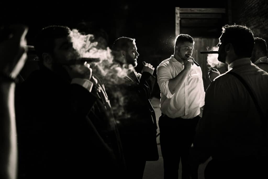 groom and groomsmen smoking cigars waiting for wedding to start by Roy Serafin Photo Company