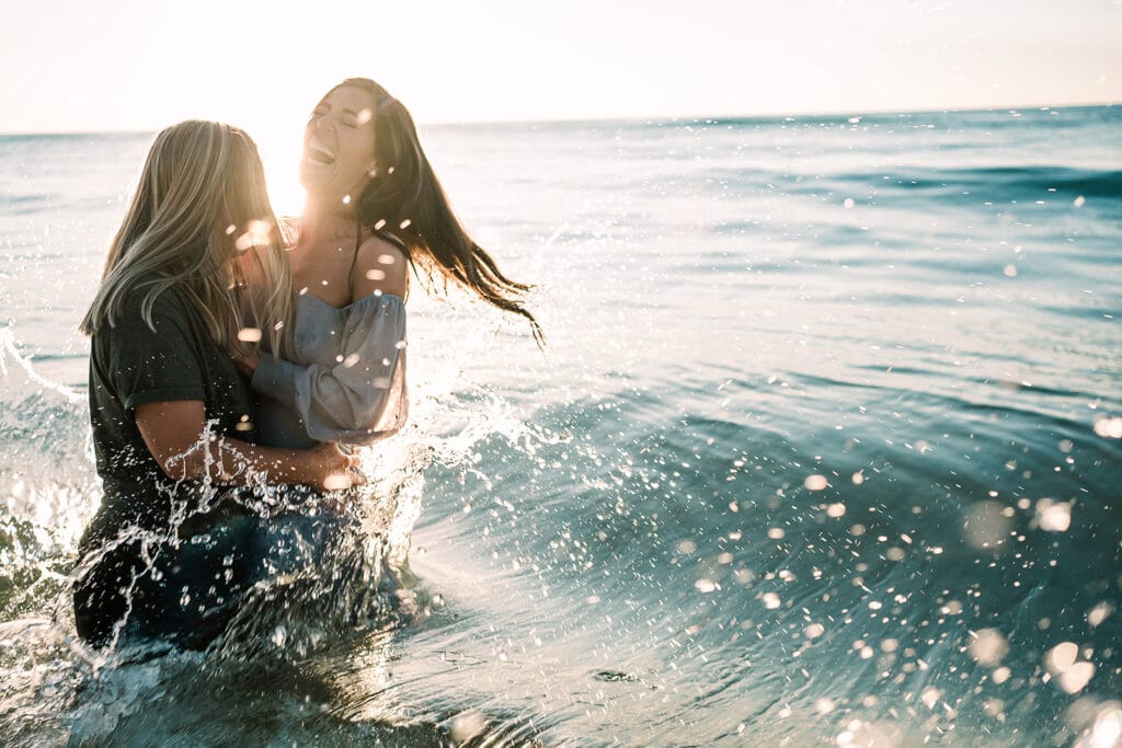 couple playing and splashing in the ocean by Roy Serafin Photo Company