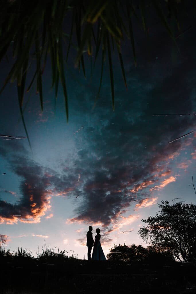 couple silhouetted against blue and pink sky at sunset by Roy Serafin Photo Company