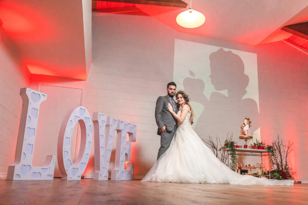 bride and groom posing for photo with large LOVE letters details by 360 Emotions