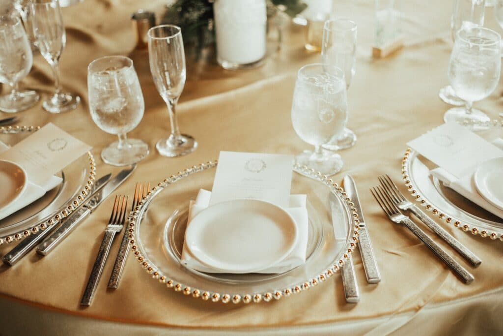 place setting of crystal, gold accents and blond wood
