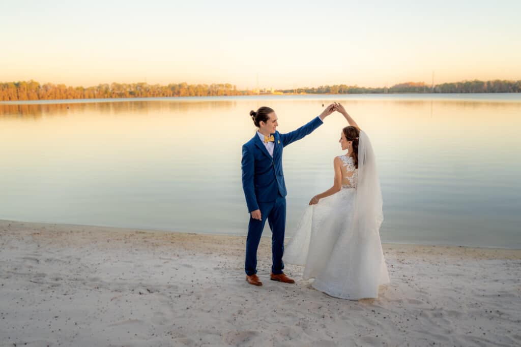 bride and groom dance at the edge of a serene and calm lake