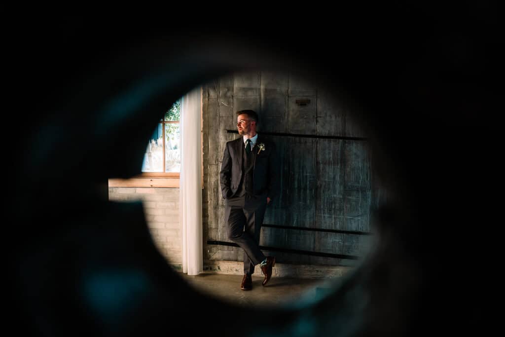 door lock lens photo of groom against a wooden door by Roy Serafin Photo Company