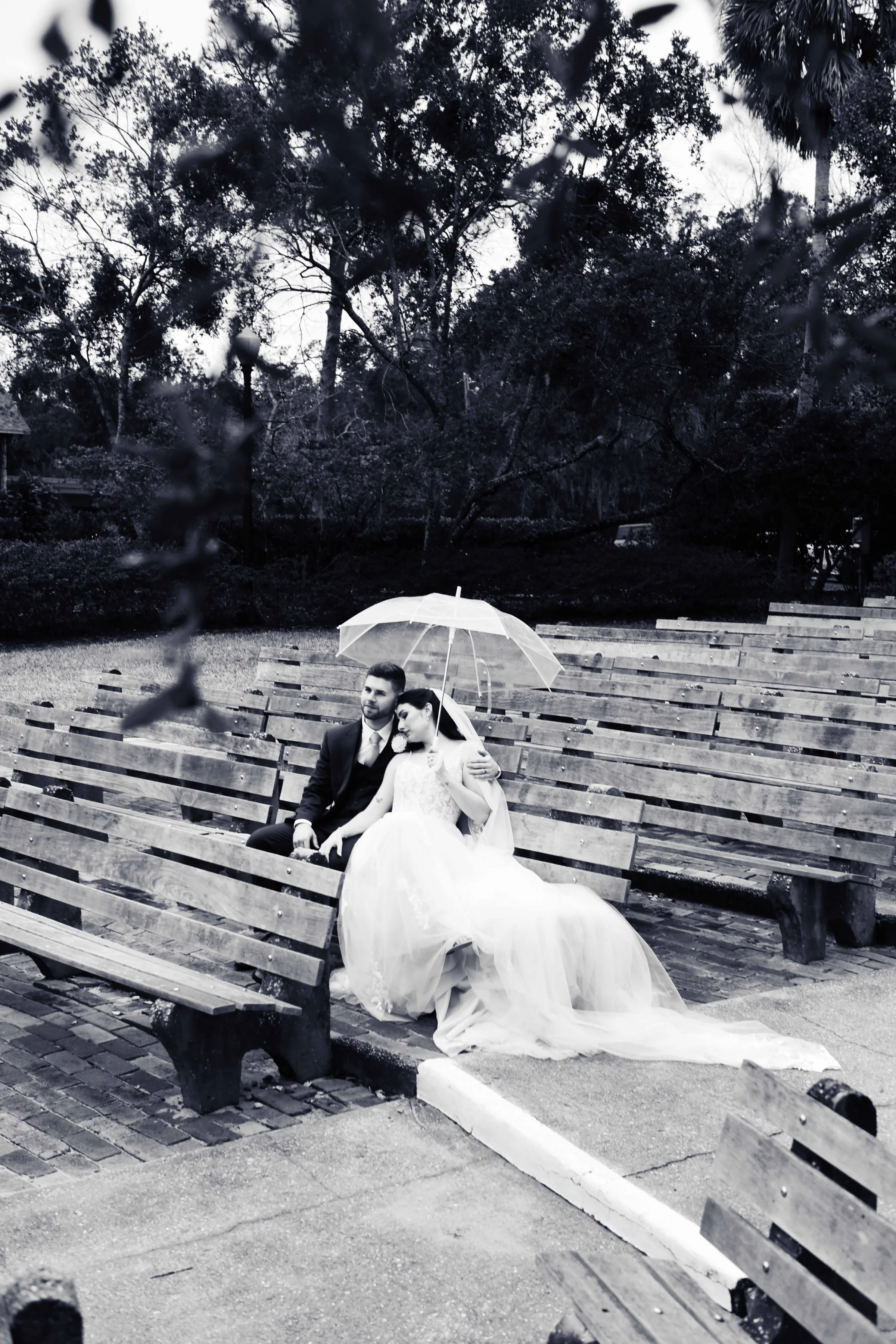 Bride and groom sharing a quiet moment under a clear umbrella during an outdoor wedding ceremony.