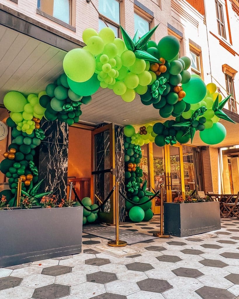 shades of green balloons with wood limbs outside a restaurant by Fab and Float events