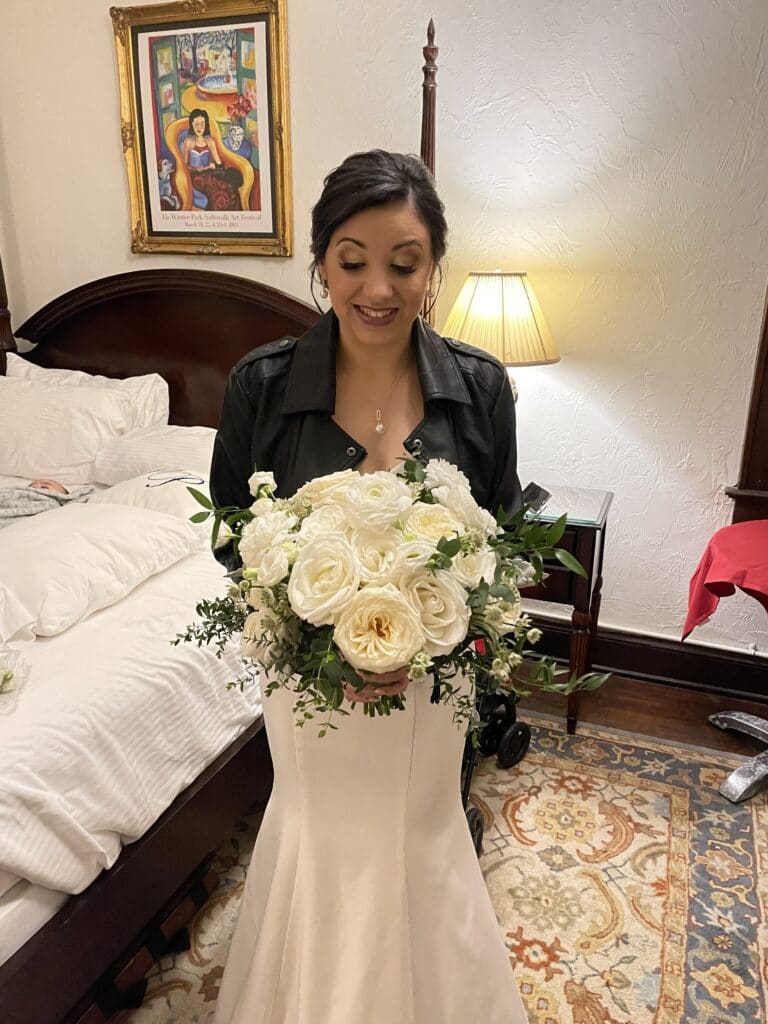 bride waiting in bridal ready room looking at large bouquet of white peonies and roses by Petals and Stems Market