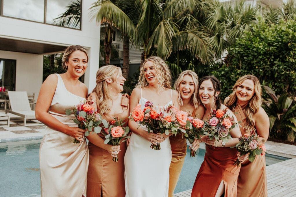 bride with her bridesmaids in shades of champagne to rust with flowers by Petals and Stems Market