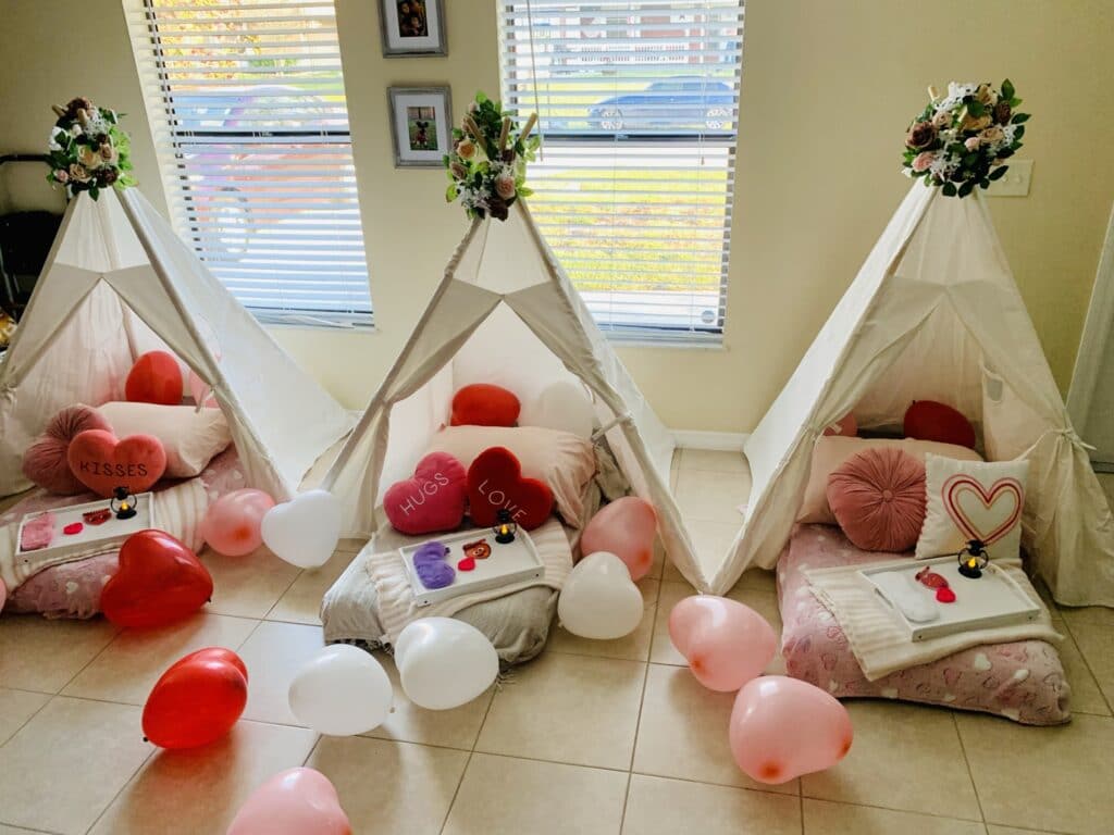 Valentines set up with red, white, and pink balloons, tents, and pillows.