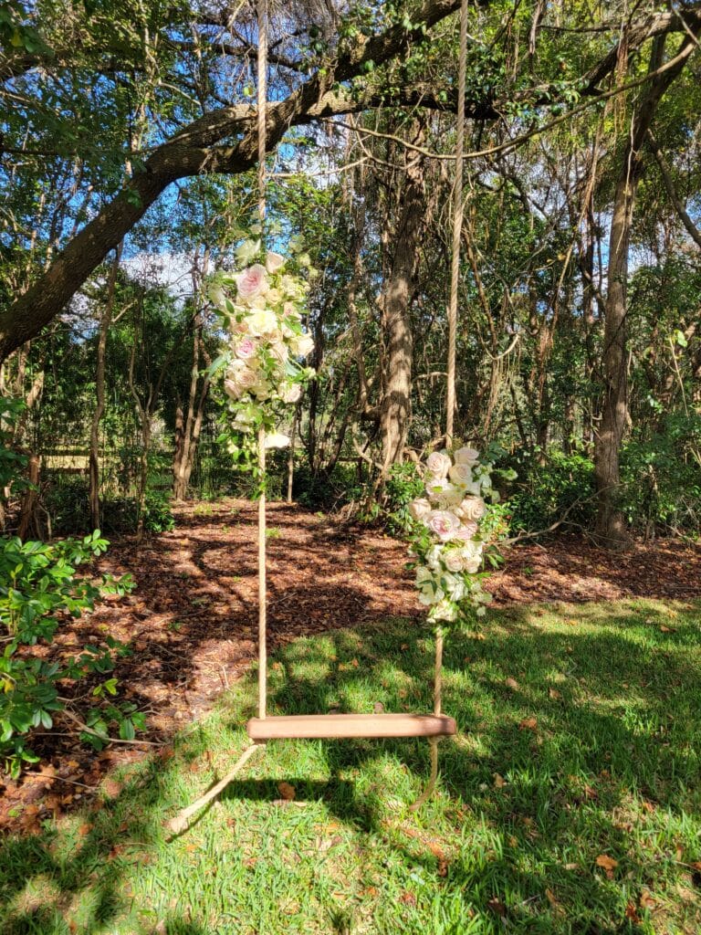 Sweetheart swing adorned with cream and pink roses hanging from an oak tree