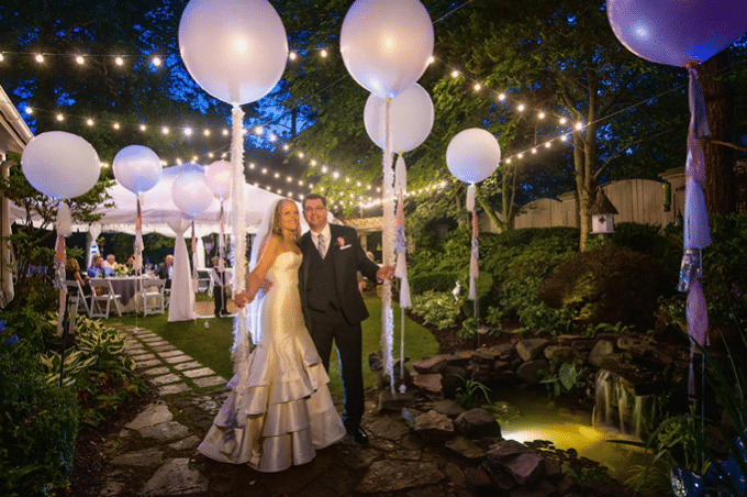 bride and groom at outdoor reception with market lights and big white balloons from Dawn Gilmore Productions
