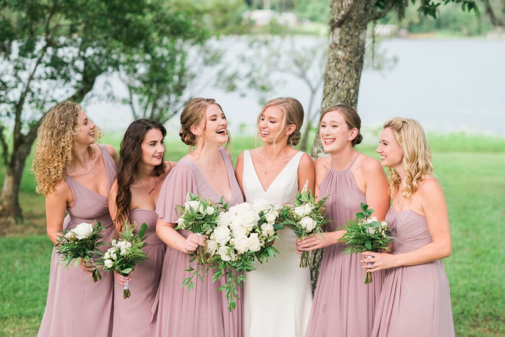 bride with white and green bouquet and bridesmaids in different styled blush dresses with bouquets of white and greenery by Petals and Stems Market