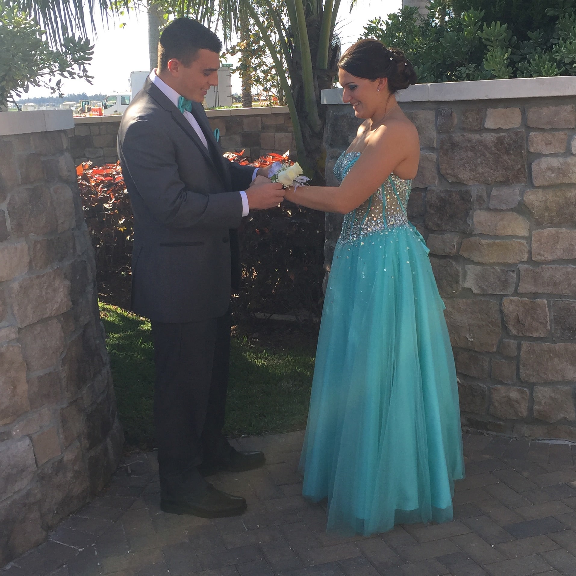 high school couple getting corsage with girl in turquoise dress