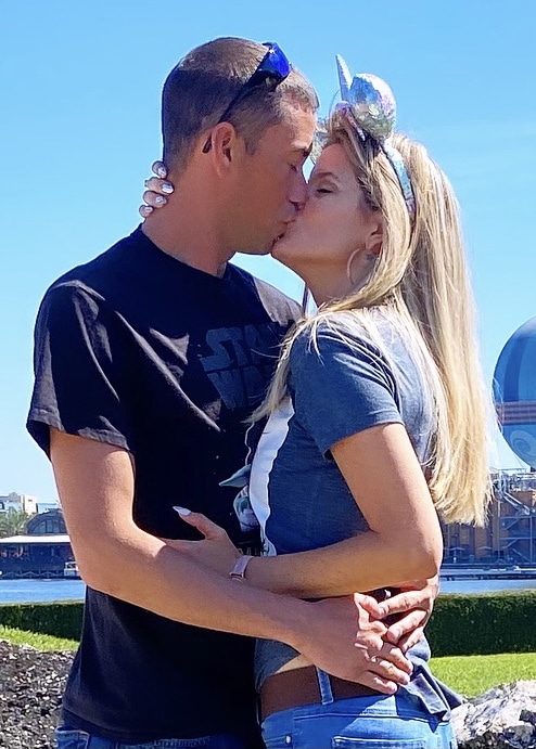 Woman wearing Disney ears kissing her fiance.