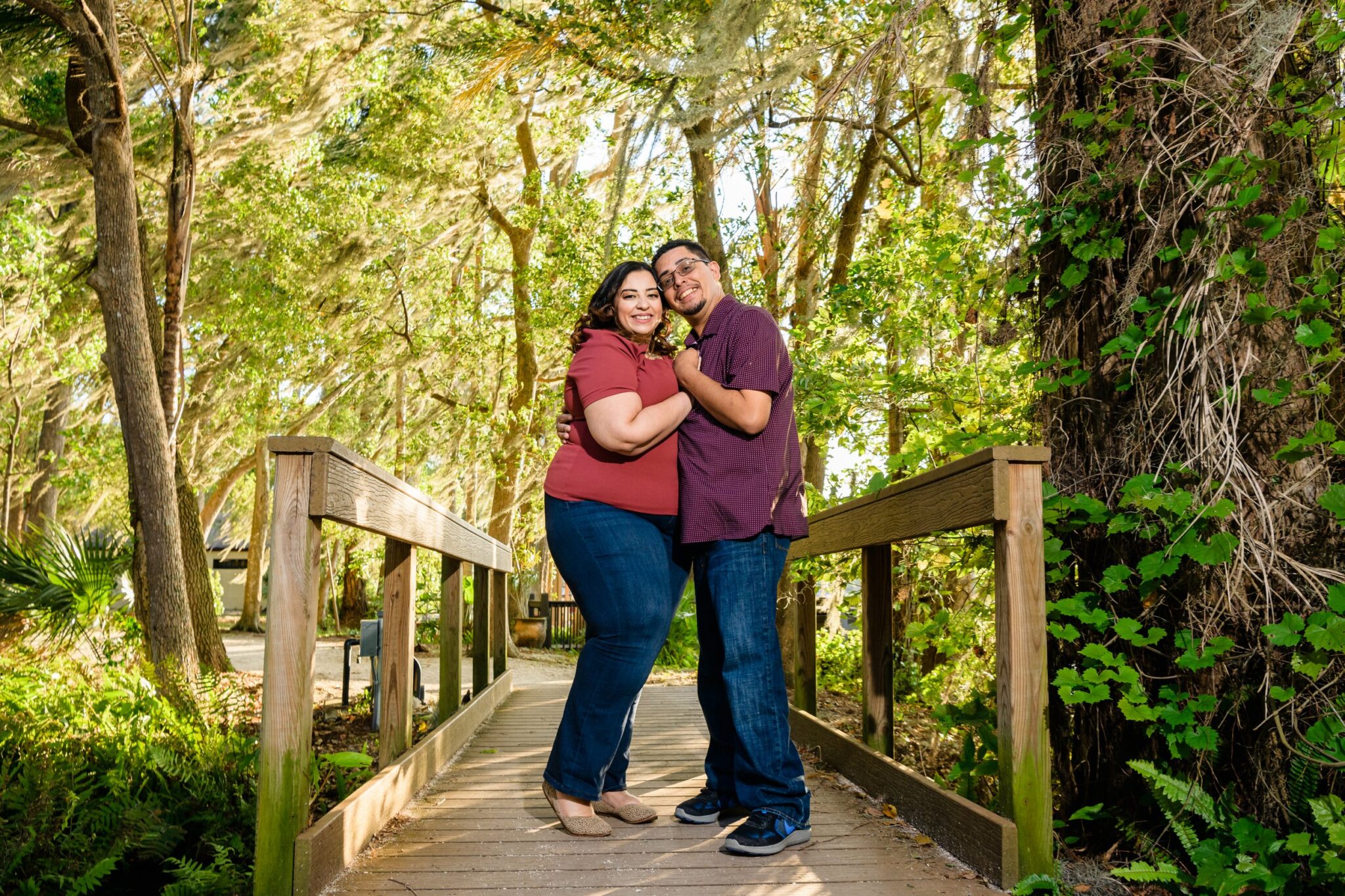 couple on a bridge in the woods smiling for engagement photo session