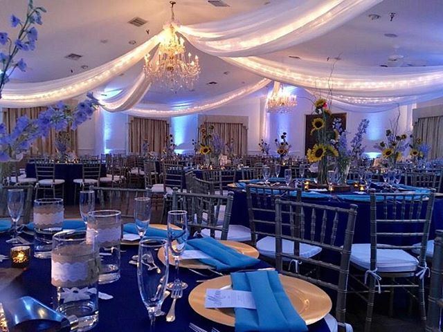 room draped with white silk, tables set with gold chargers and navy napkins