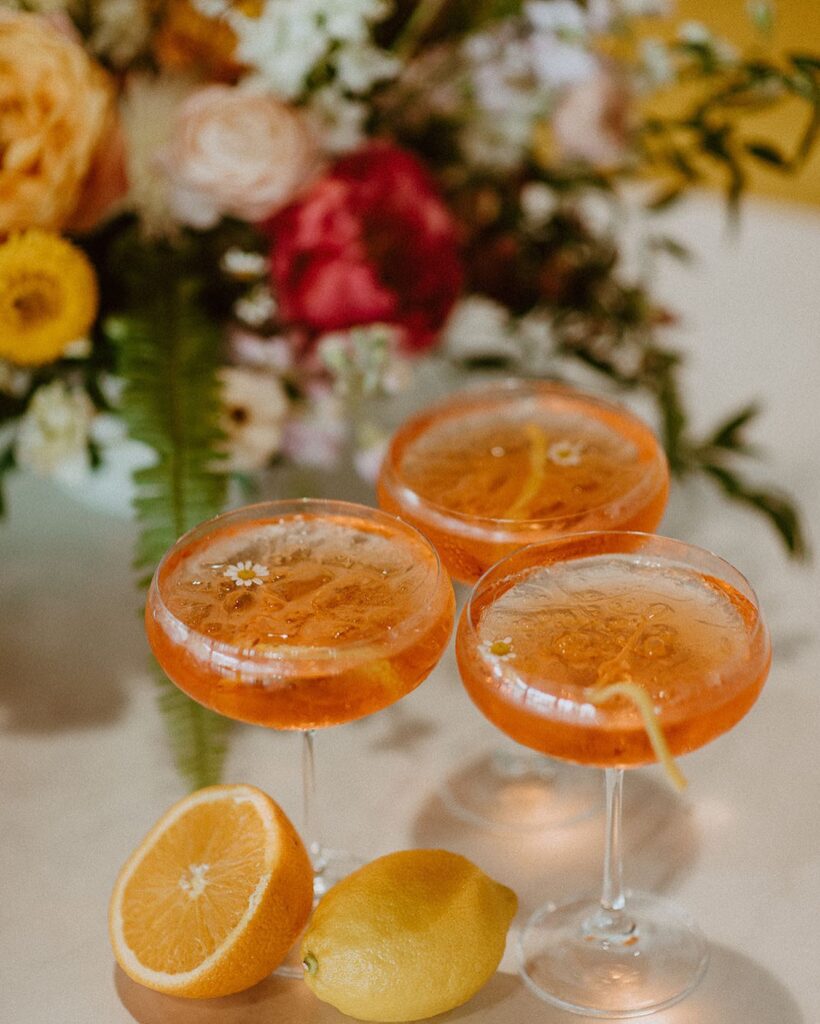 orange and lemon specialty drink on a table with floral bouquet