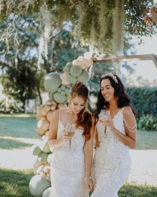 brides drinking against a balloon arch with champagne poured by My Bar Service