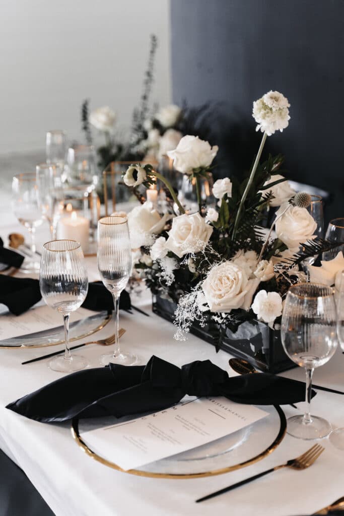 black and white table setting with white flowers and white candles and gold accents at The Black Barn