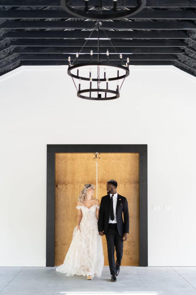 bride and groom in front of wooden doors at The Black Barn
