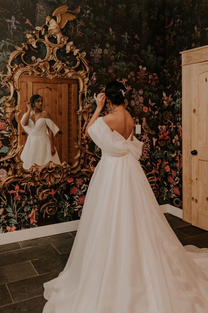 bride looking at her reflection in an ornate mirror at The Black Barn