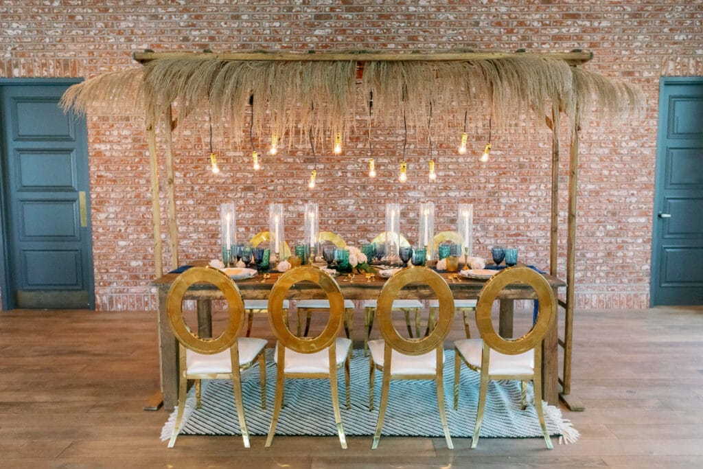 table under palapa roof inside event room against a brick wall
