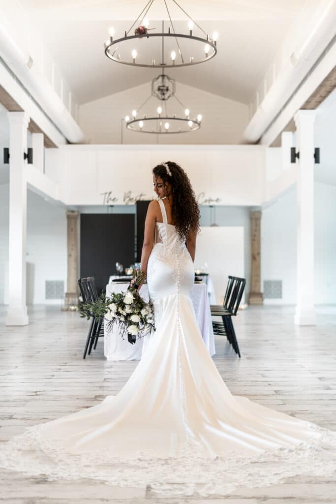 wedding gown and train on a white floor in a white ballroom at The Black Barn