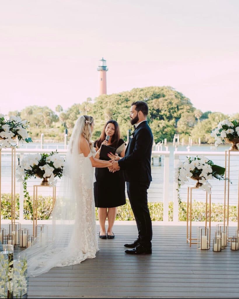 Bride and groom exchanging vows in front of a life house on a dock