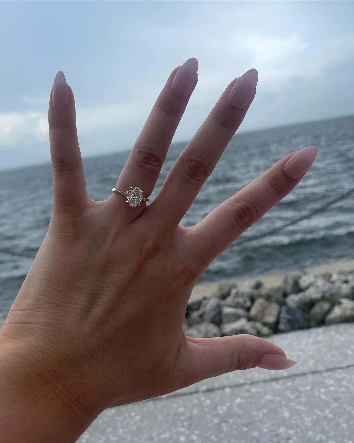 engagement ring held up against the sky