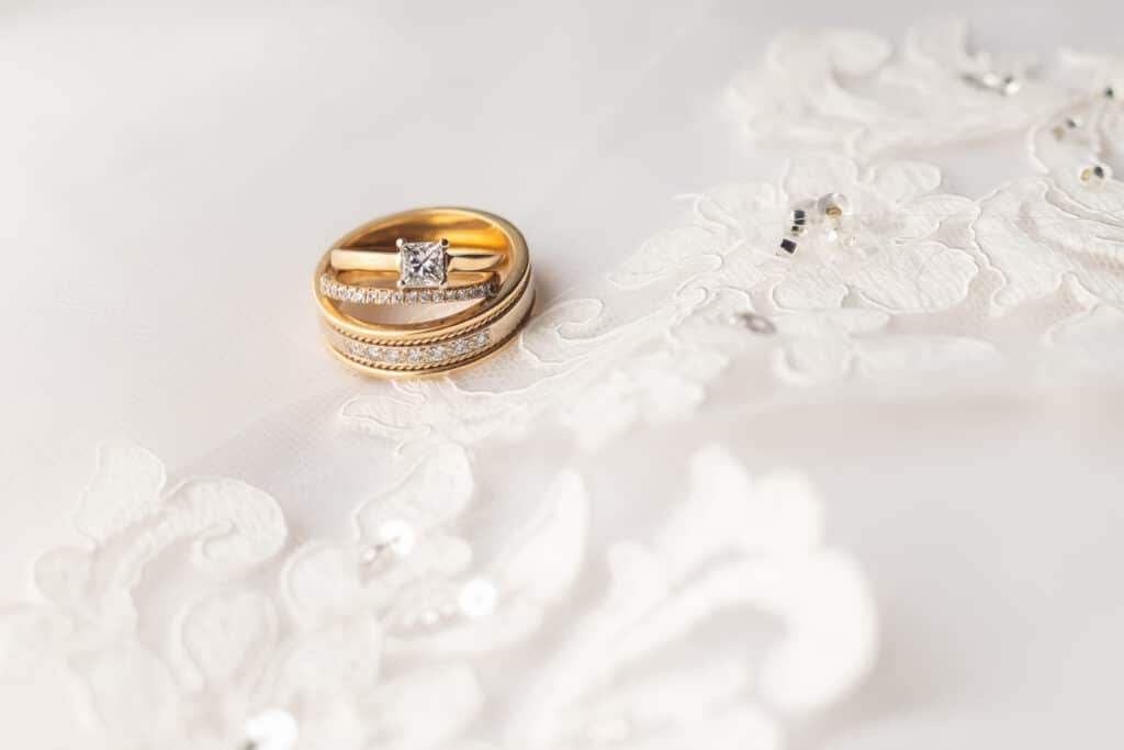 photo of wedding ring and engagement ring resting on lace veil by SMO Photography