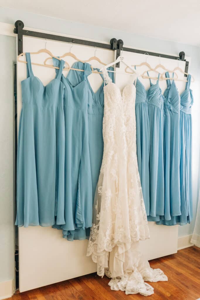 wedding gown hanging against bridesmaids turquoise gowns ready to be worn by Sydney Morman Photography
