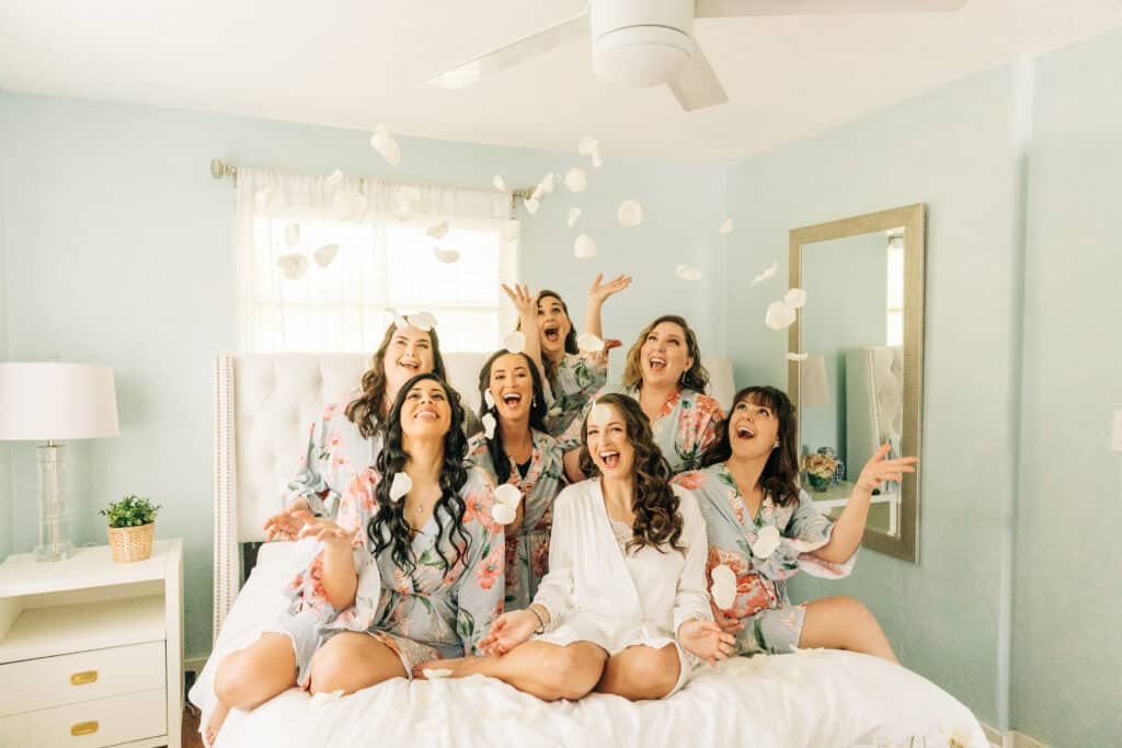 bridal party of women smiling and throwing flower petals getting ready for a wedding by Sydney Morman Photography