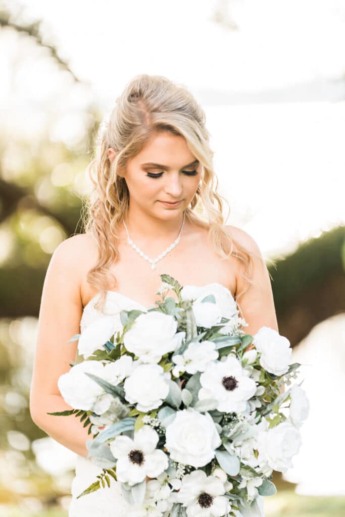 bride looking down on bouquet of silk white roses and white flowers from Wedding Day Flower Rental