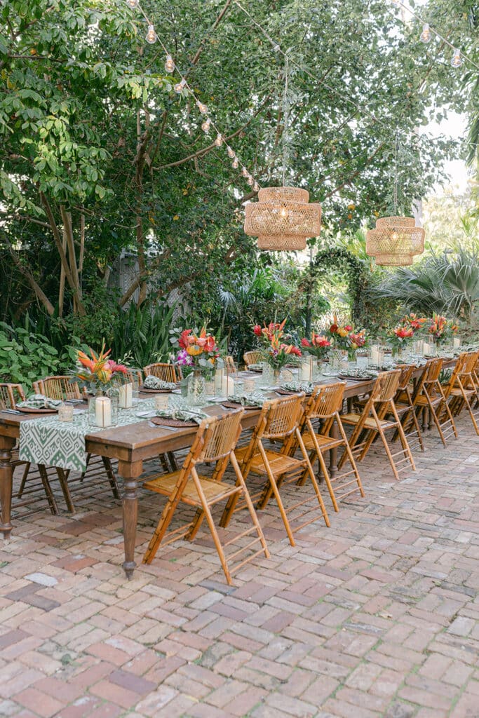 outdoor tropical ceremony reception under market lights with rattan chandeliers and tropical flower centerpieces at event planned by Just Save the Date