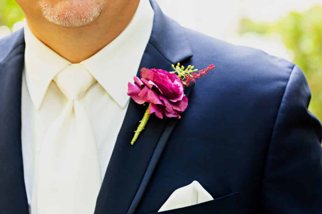 groom in navy suit with bright fuschia and lime boutonnière at event planned by Just Save the Date