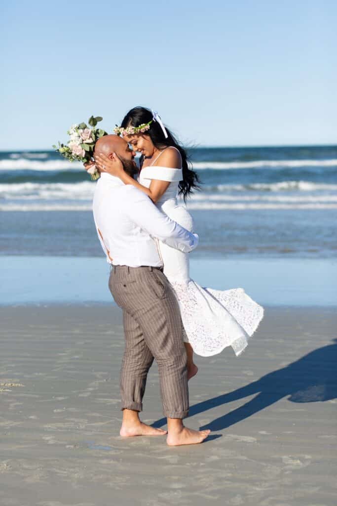 groom swing bride in her wedding gown around on the beach at the ocean by Amy Britton Photography