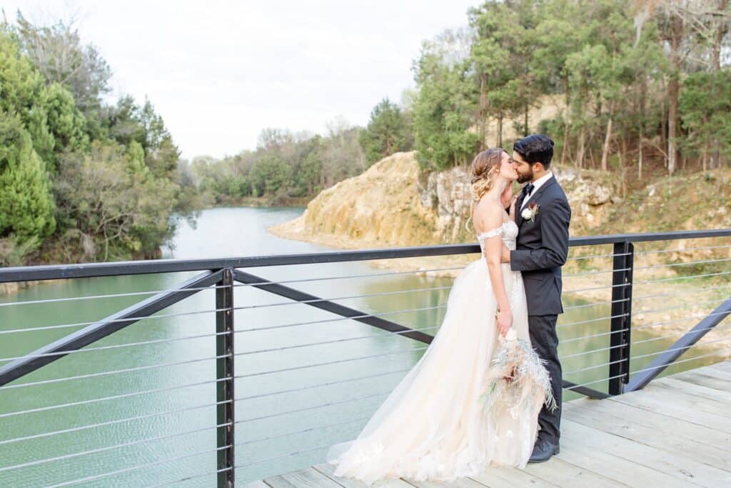 bride and groom kissing on a contemporary black and wire bridge over a river by Amy Britton Photography
