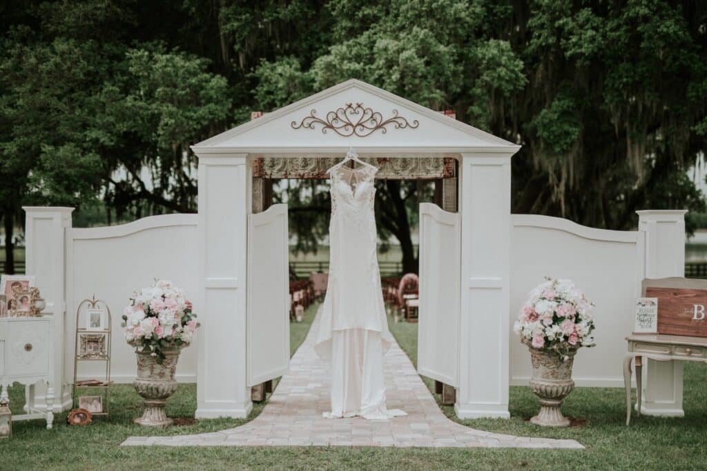 wedding dress hanging in white pillared outdoor altar by Making It Matthews