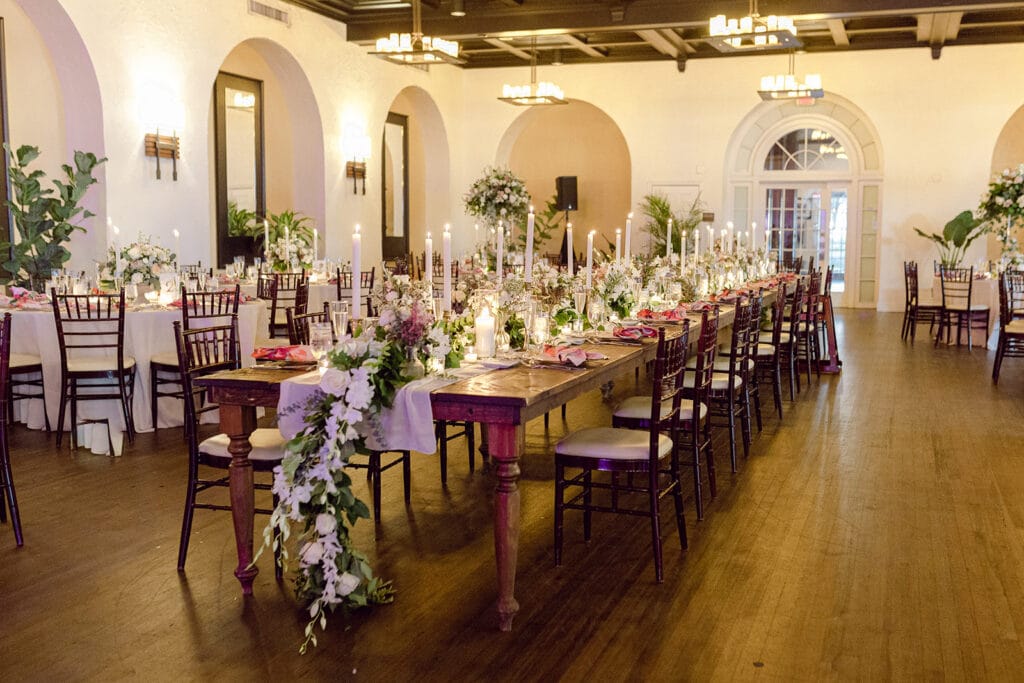long tables with long pink and white floral centerpieces and candles at event planned by Just Save the Date