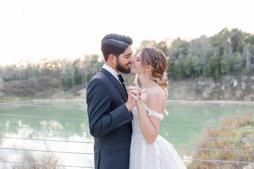 bride and groom kissing standing at the edge of a lake by Amy Britton Photography