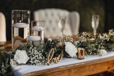 table scape with greenery and white flowers, gold accents and champagne glasses by Making It Matthews