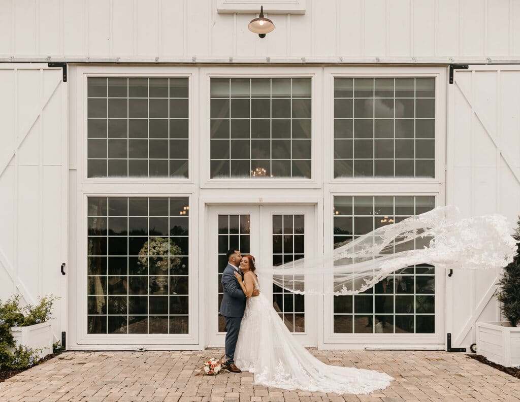 bride and groom hugging in front of an industrial building of windows coordinated by SMS Events & Design