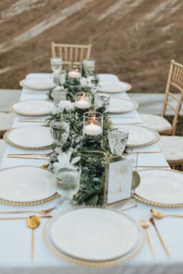contemporary table setting with white chargers and plates and gold silverware by Making It Matthews
