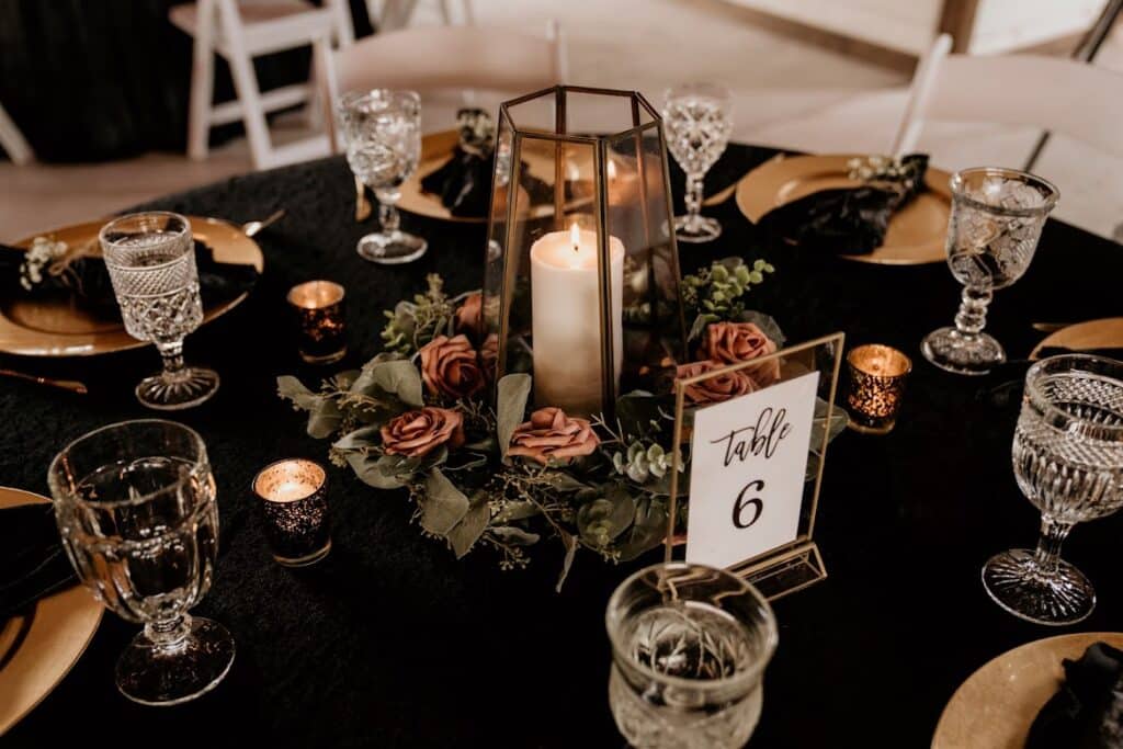 table setting with candles, water glasses and black tablecloth by Making It Matthews