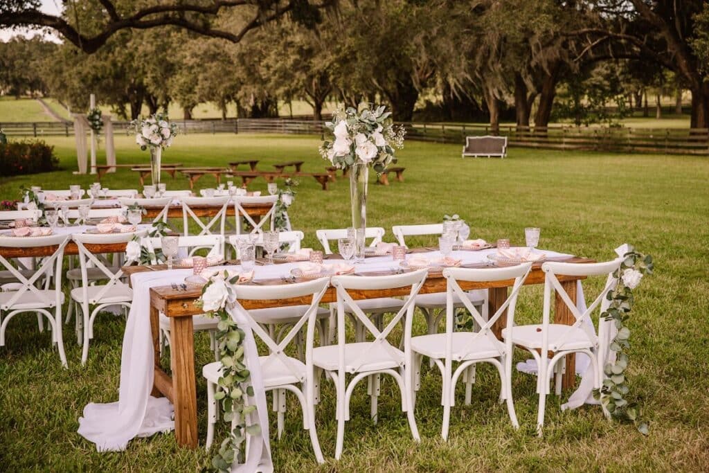 outdoor reception with farm tables, white draping and white chairs by Making It Matthews