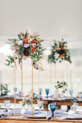 wood table setting with tall centerpieces and blue glass accents by Making It Matthews