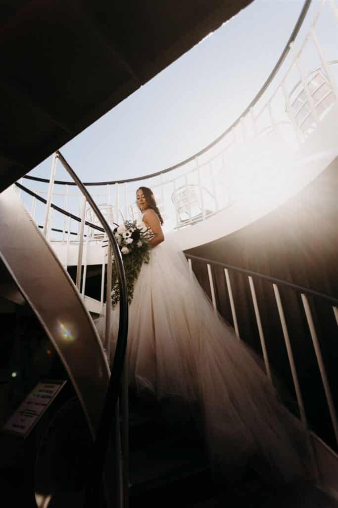 bride walking up a staircase with wedding train behind her coordinated by SMS Events & Design