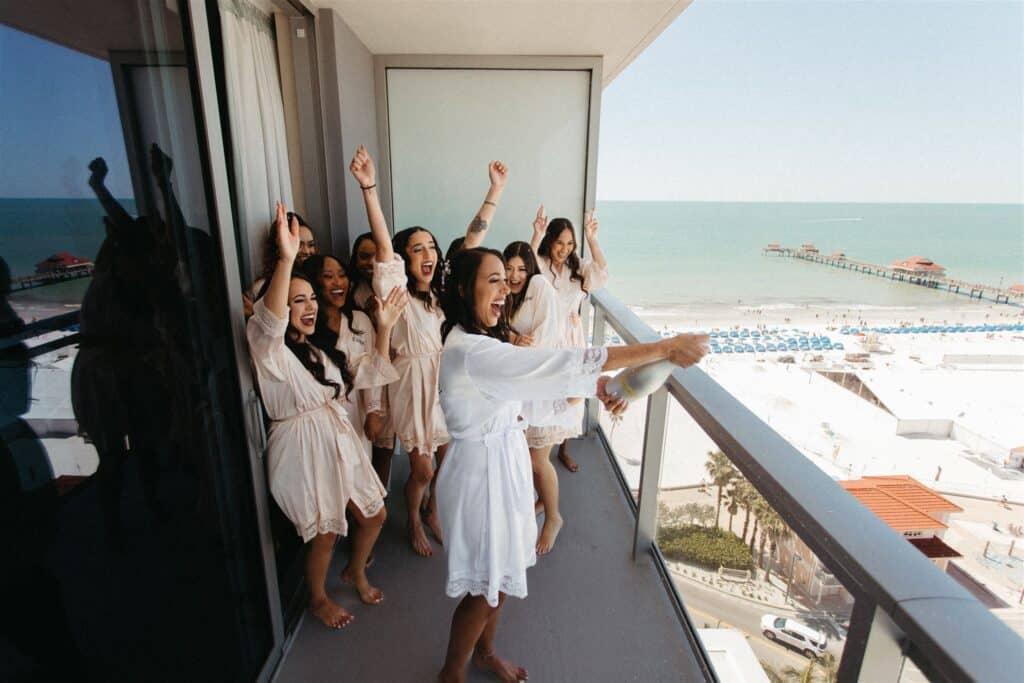bridal party celebrating on the balcony of a tall building by the beach coordinated by SMS Events & Design